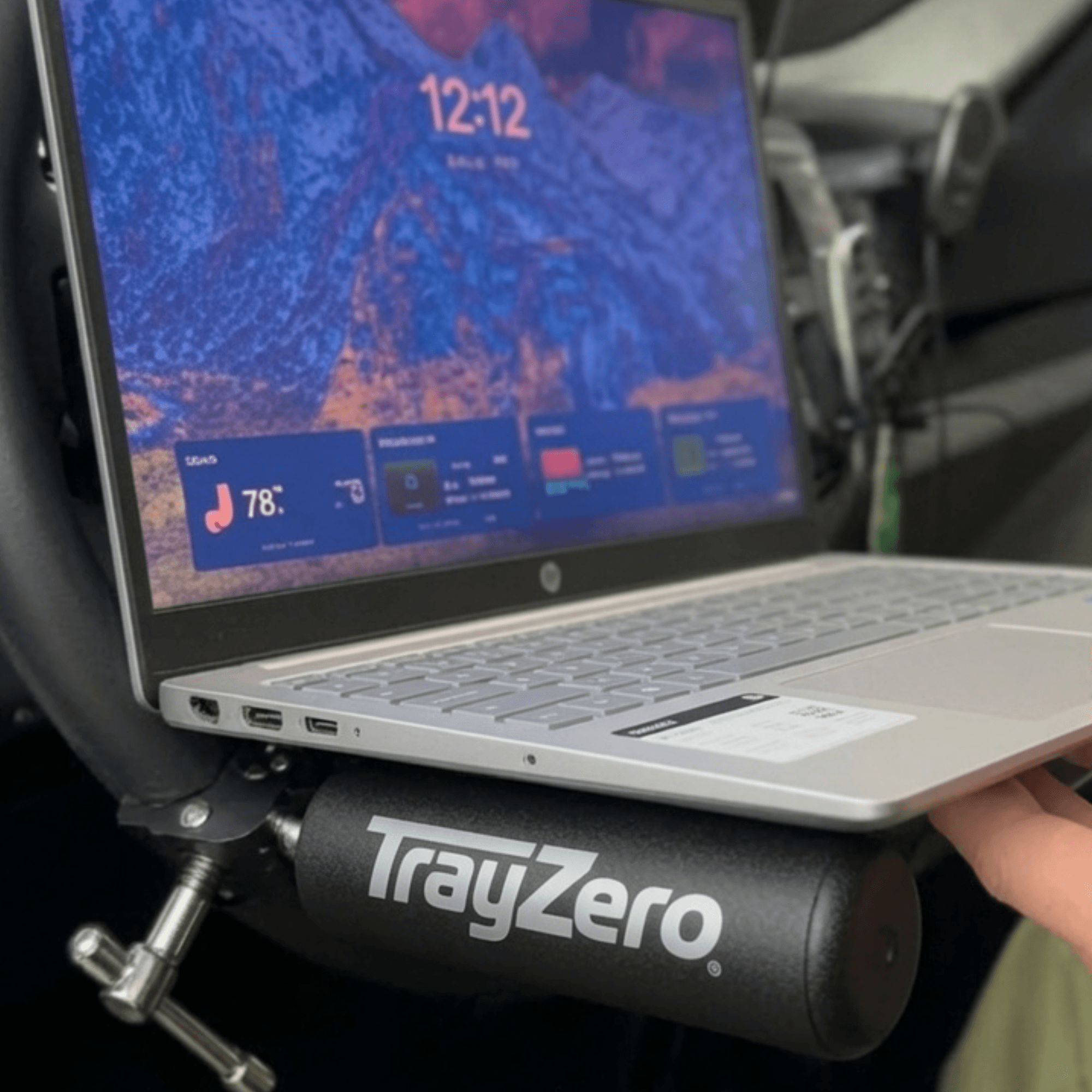 Laptop resting on TrayZero supports attached to a steering wheel in a parked vehicle